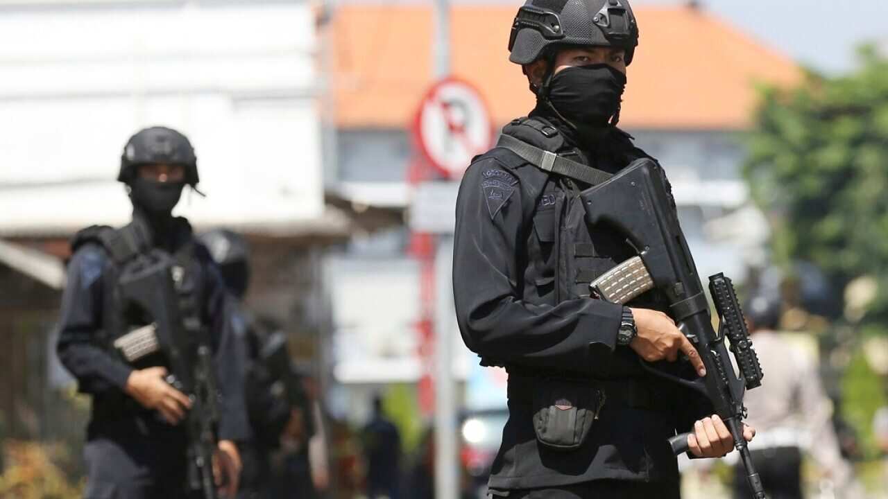 Officers stand guard outside the local police headquarters following the attack in Surabaya.