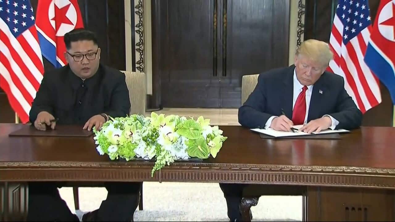 US President Donald Trump signs an agreement with North Korean leader Kim Jong-un.