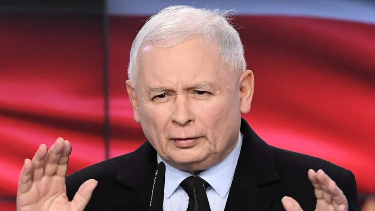A man with white hair wearing a suit and tie