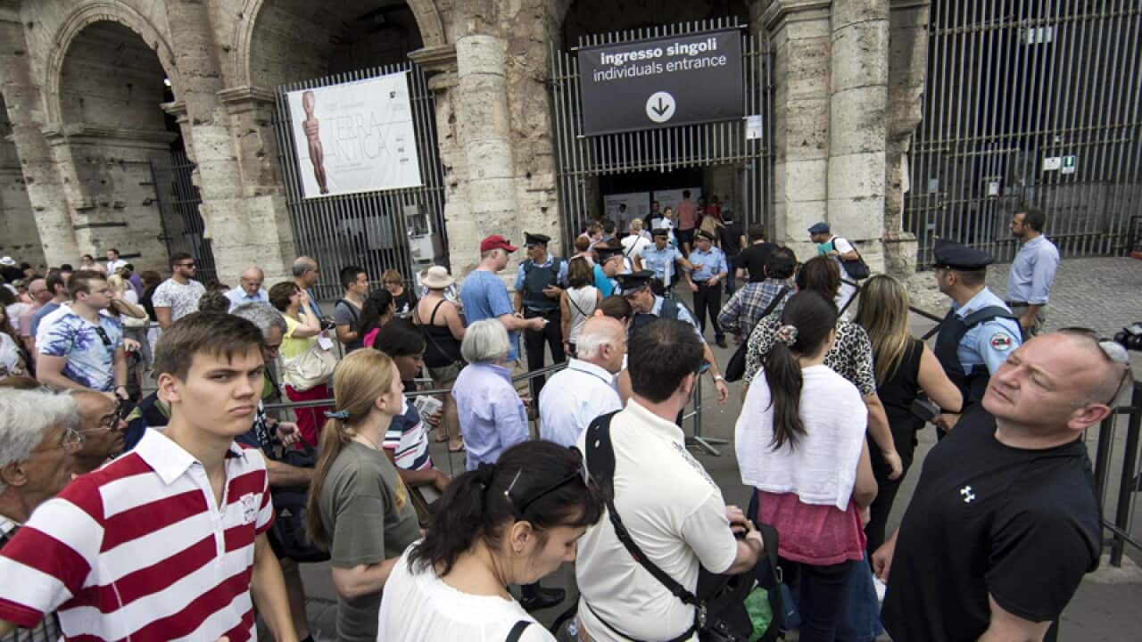 Tourists queue in front of the Colosseum