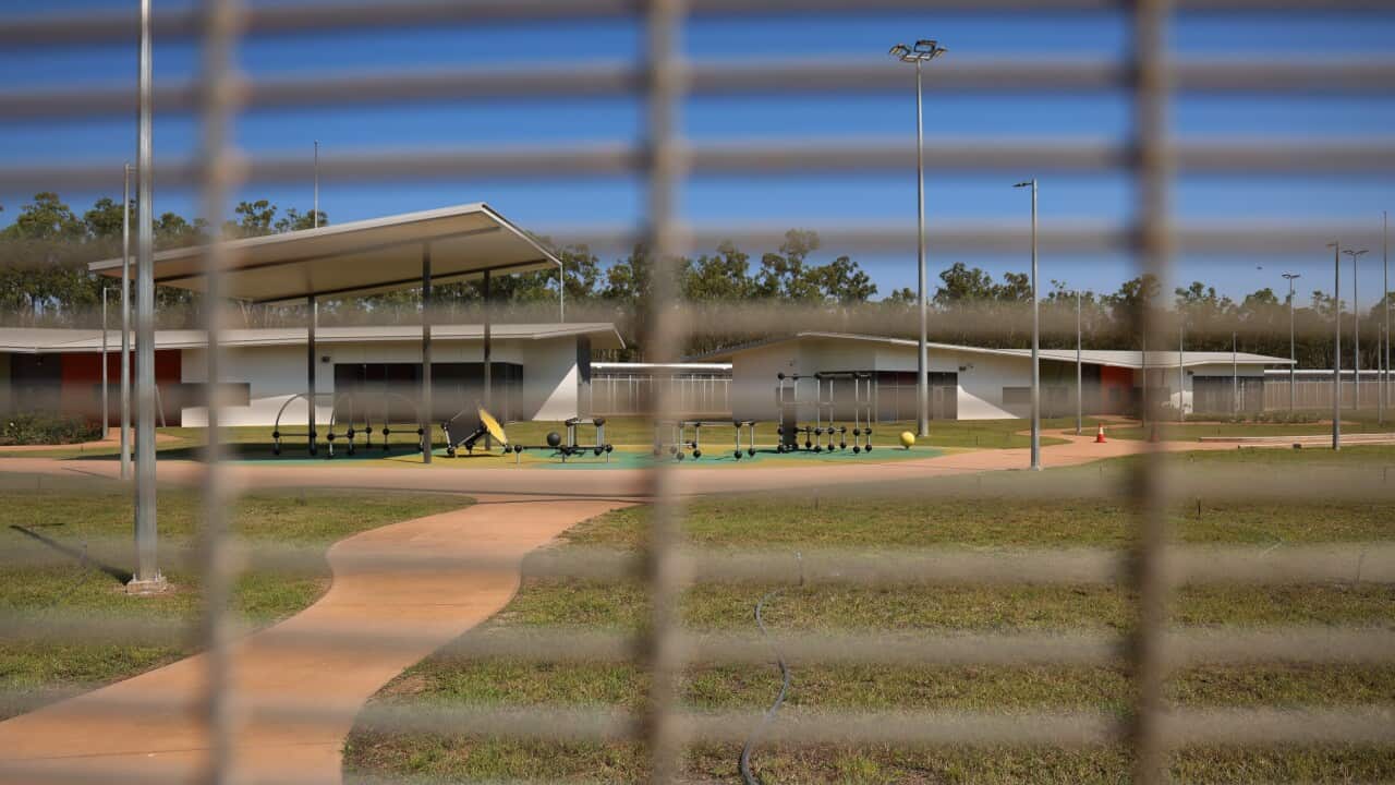 An outdoor play equipment area with a fence in front of it, obscuring the view.