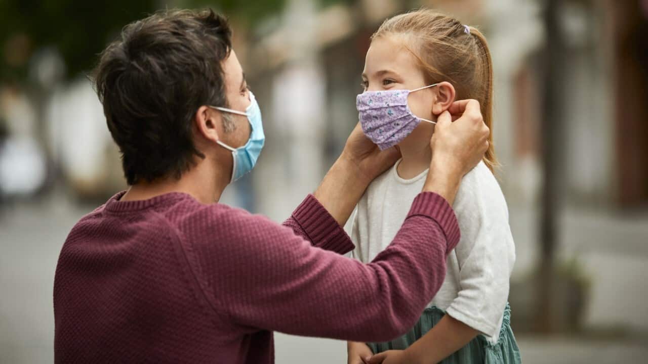 Father helps daughter with mask