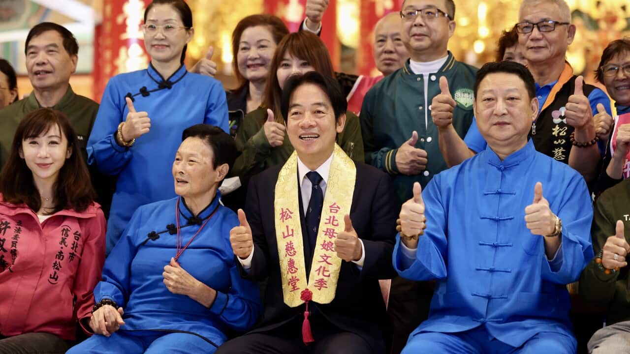 DPP presidential candidate William Lai holds his thumb up and smiles in a group photo taken a temple in Taiwan.