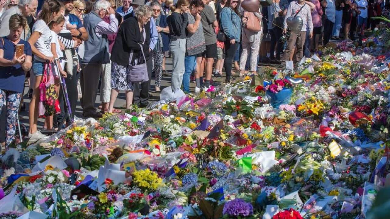 Members of the public look at a makeshift memorial