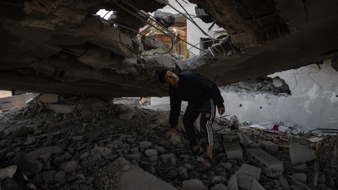 A young man stands amid the rubble, inspecting the damage after an airstrike.