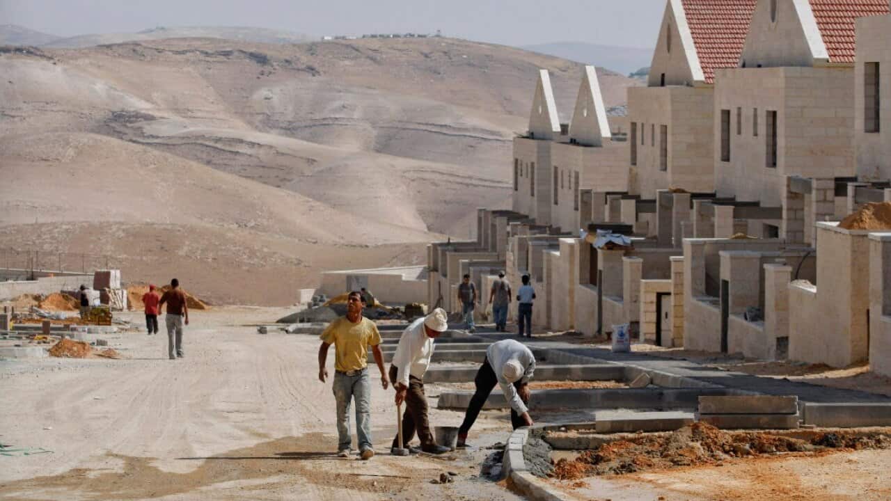 FILE: Palestinian men work at a construction site in the West Bank Jewish settlement.