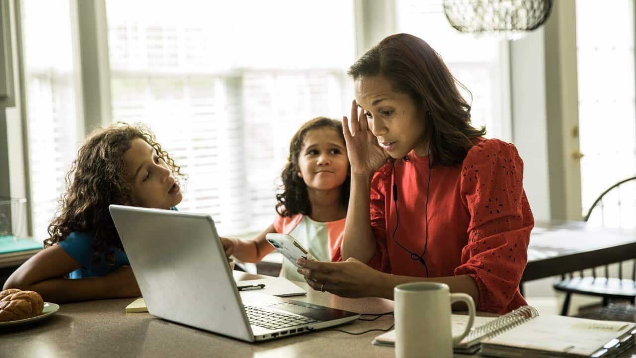 Mother working from home with children in background