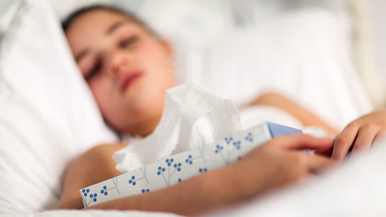 Girl in bed holding box of tissues