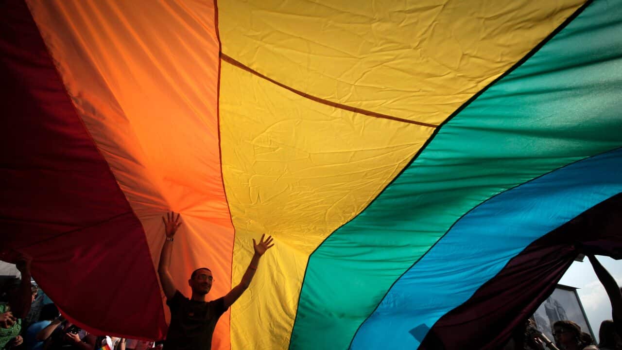 A man is seen underneath the rainbow flag