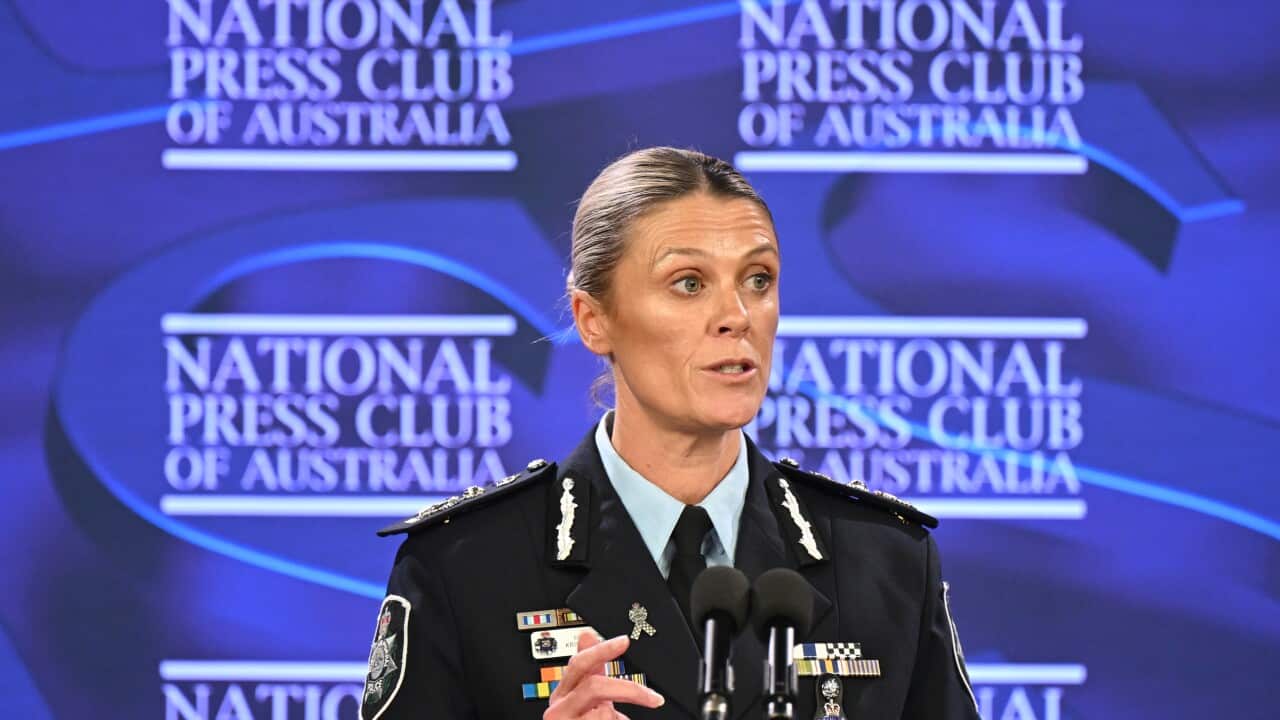 Krissy Barrett speaking at a podium with a blue National Press Club display behind her.