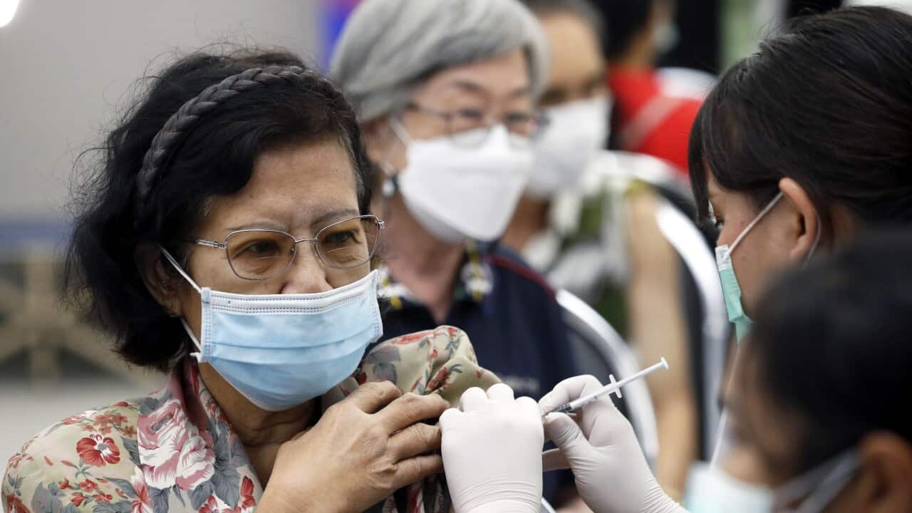 A middle aged woman wearing glasses and a face mask getting a vaccine