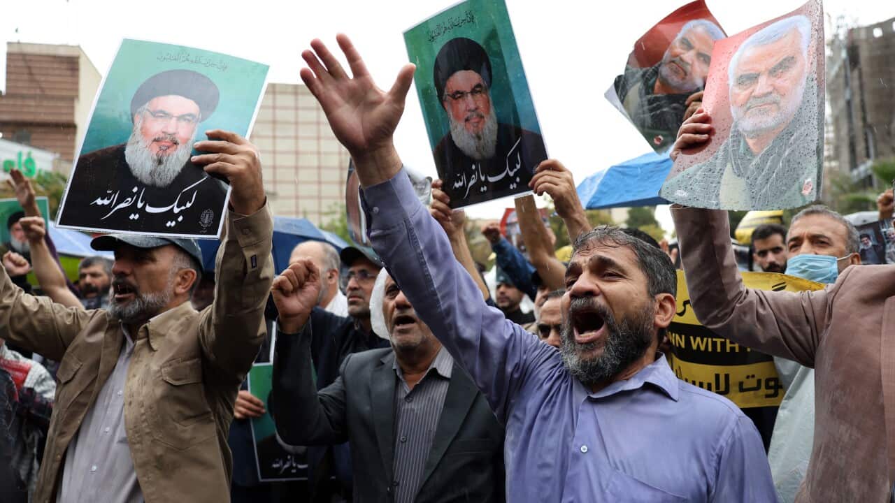People in the streets at a protest. Some are holding pictures of late Hezbollah leader Hassan Nasrallah.