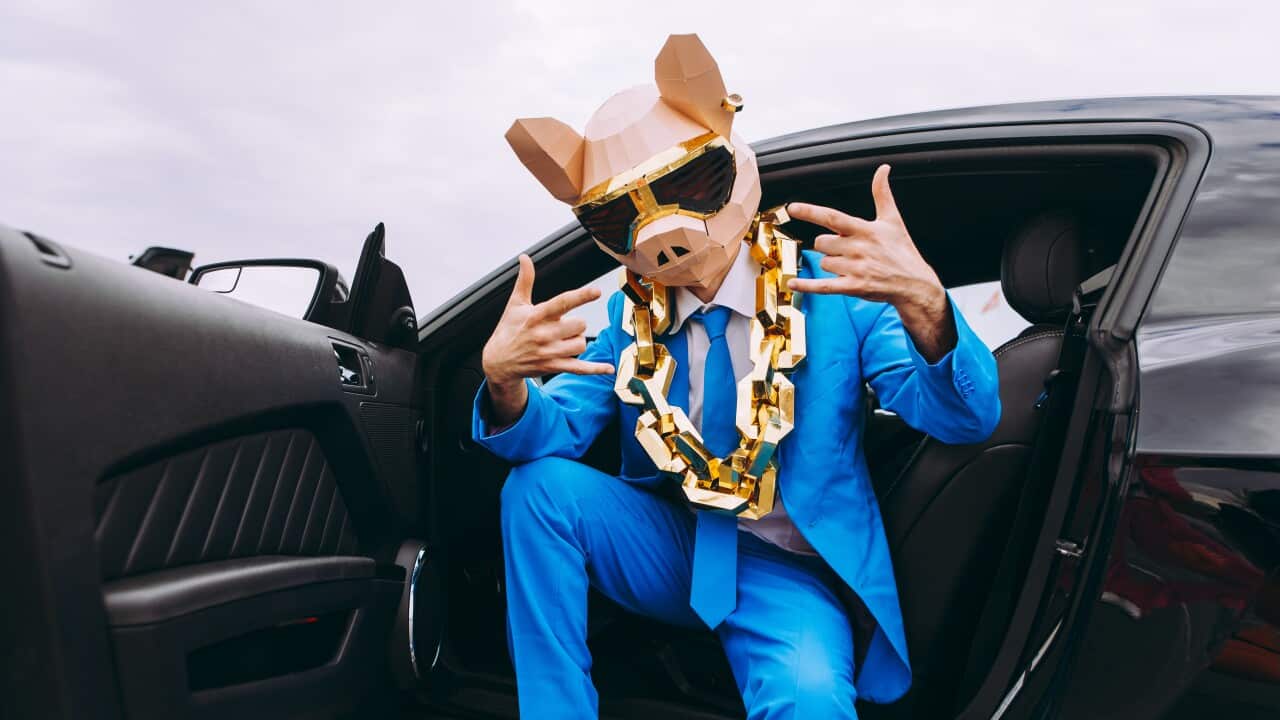 Funny character in animal mask and blue business suit sitting in car and gesturing