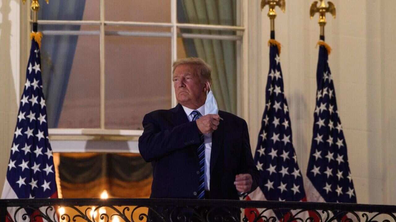 US President Donald Trump takes off his mask as he arrives at the White House upon his return from Walter Reed Medical Center