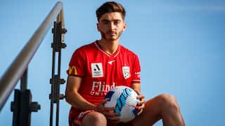 A football player wearing an Adelaide United uniform holding a ball