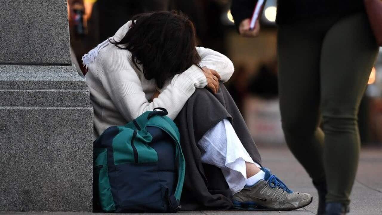 A homeless woman sits on a street corner in central Brisbane, Friday, June 9, 2017. (AAP Image/Dan Peled) NO ARCHIVING