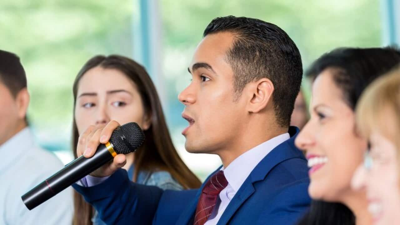 Concerned Hispanic citizen asks political candidate a question during meeting