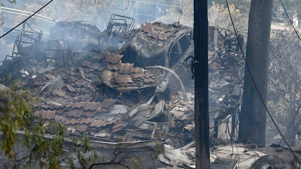 A burnt out car and the rubble of a home