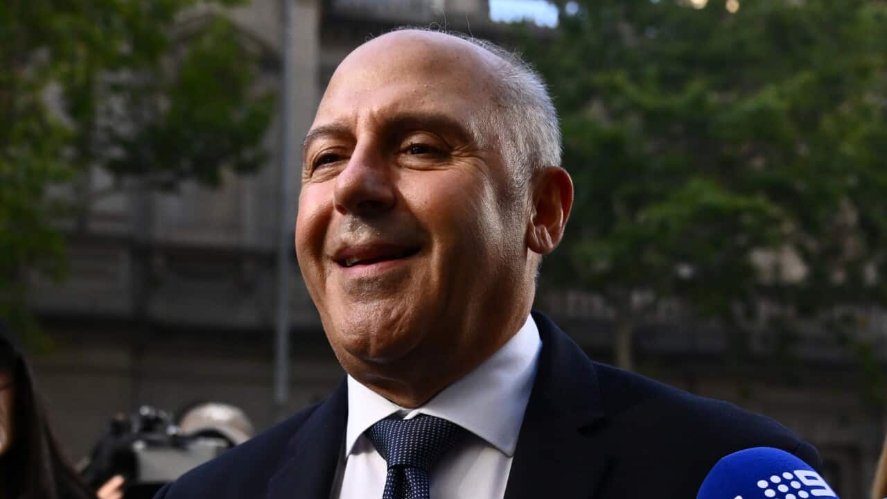 A smiling man speaks into a reporter's microphone.