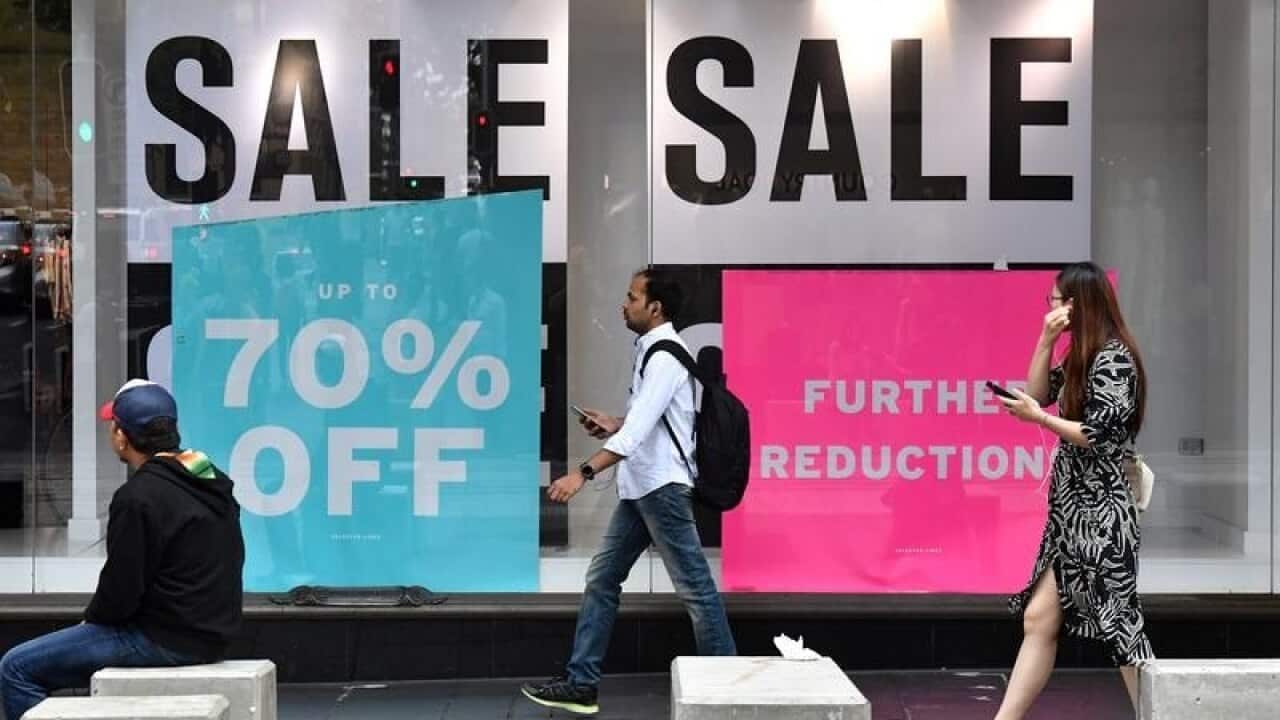 Pedestrians walk past a fashion store in Sydney