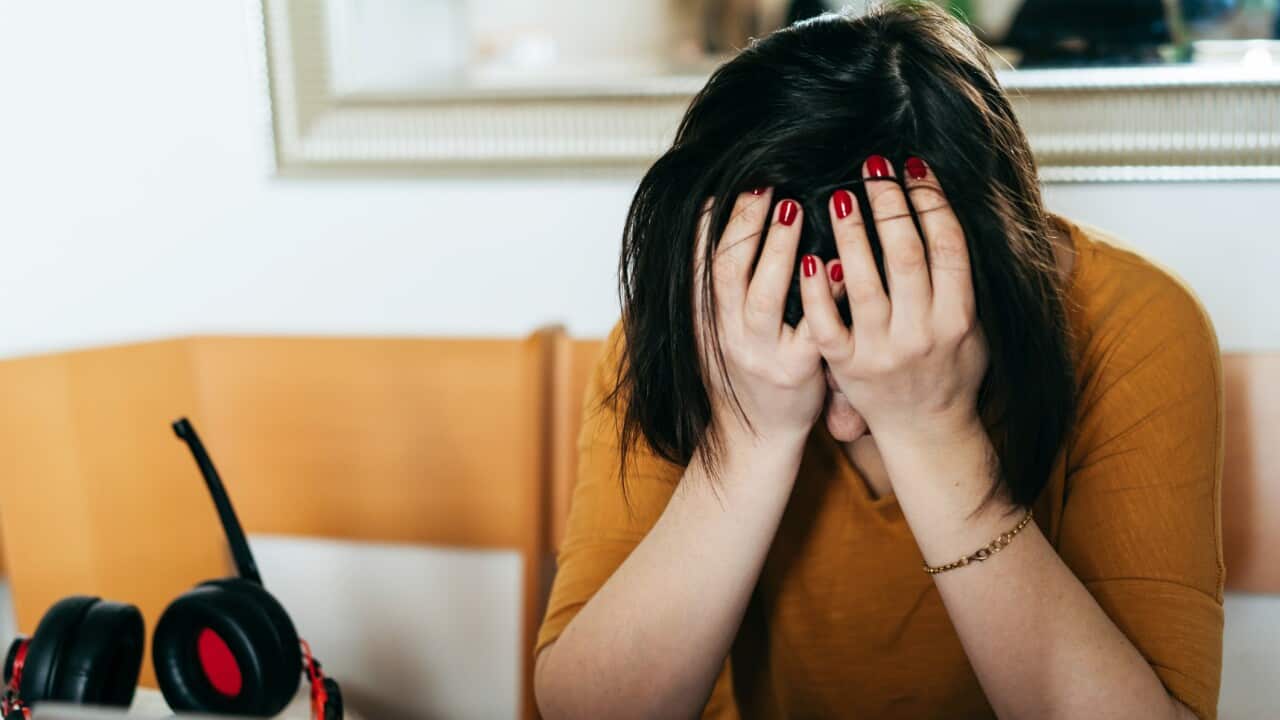 A middle-aged woman sitting in the kitchen , unhappy