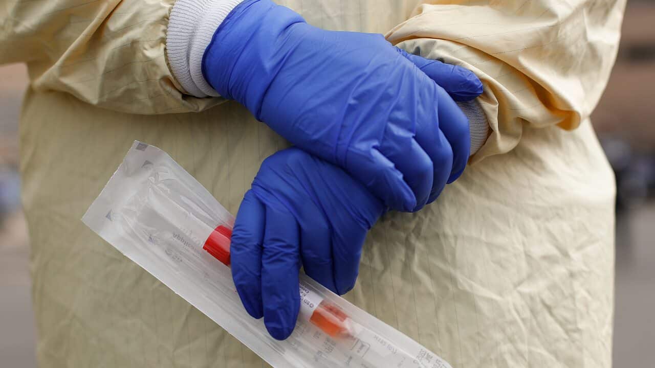 A nurse holds a swabs and test tube kit to test people for COVID-19.