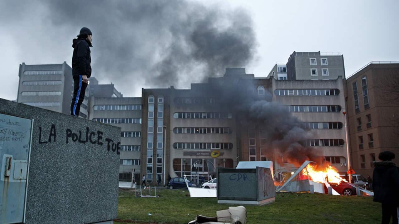 A man stands on a wall with a slogan reading: 'Police kills'