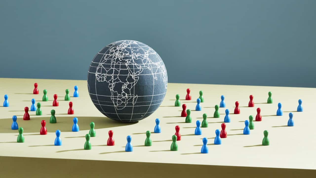 A world globe surrounded by people figurines