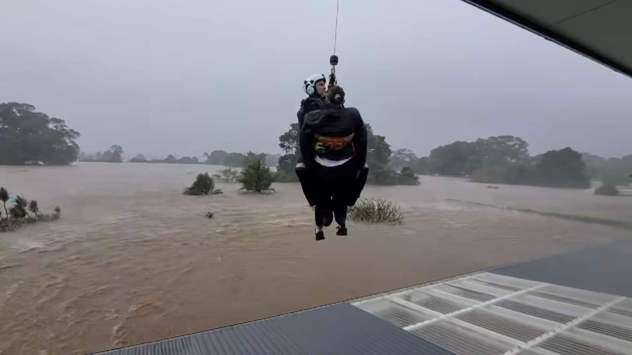 A person is winched to safety off a roof.
