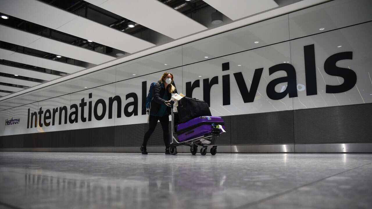 A passenger pushing luggage through the Arrival Hall of Terminal 5 at London's Heathrow Airport