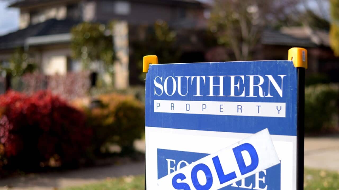 A sale sign is seen in front of a house