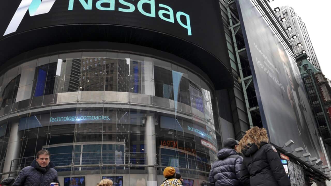 People walk past the Nasdaq Marketsite in New York's Times Square