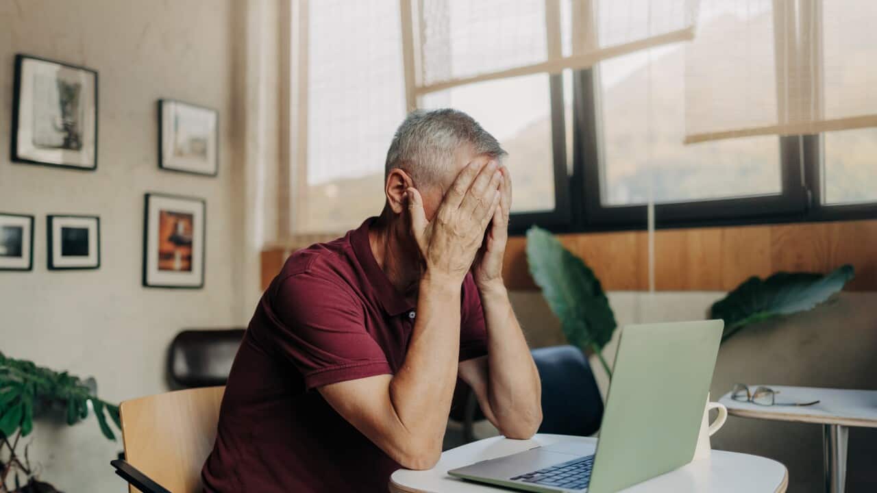 Tired and upset mature man uses laptop