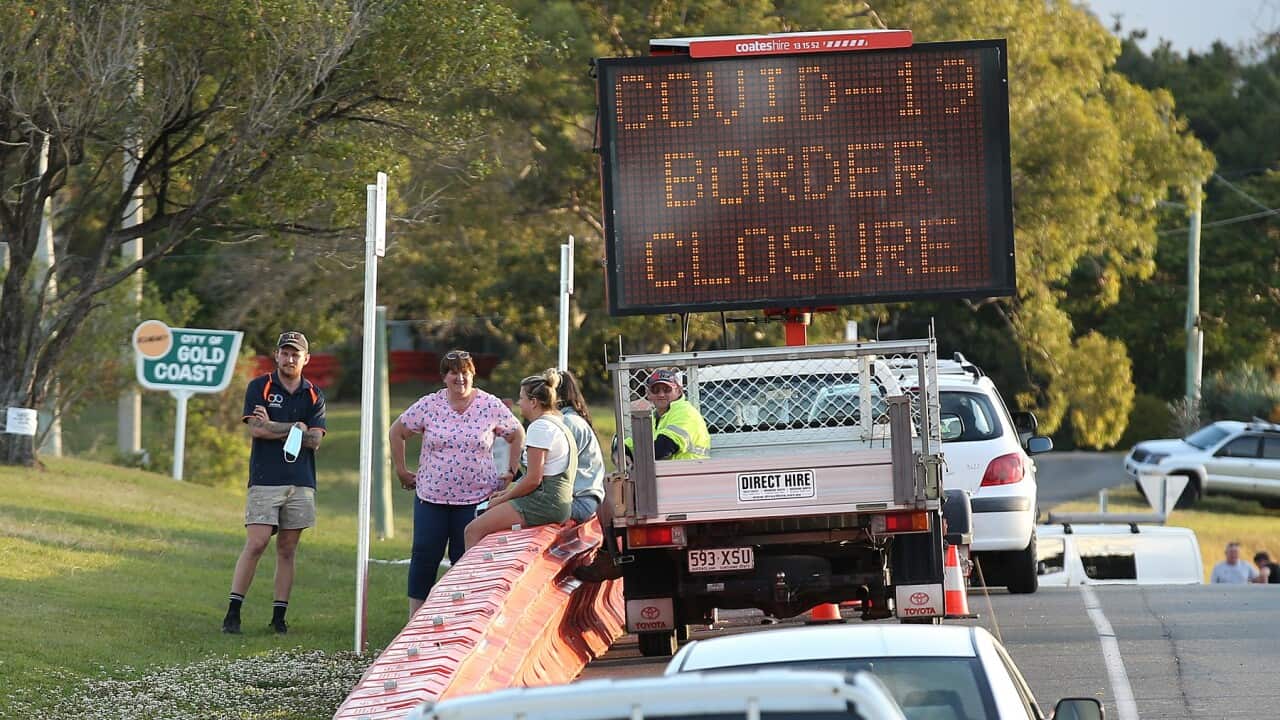 People talk to each other over the barriers at the QLD-NSW border