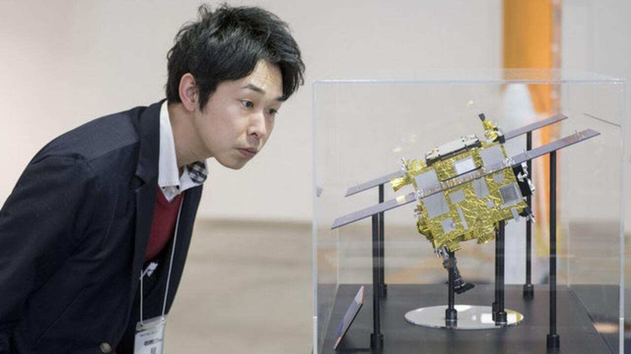 A visitor to the 2018 Japan Aerospace Show in Tokyo looks at a model of Hayabusa 2.