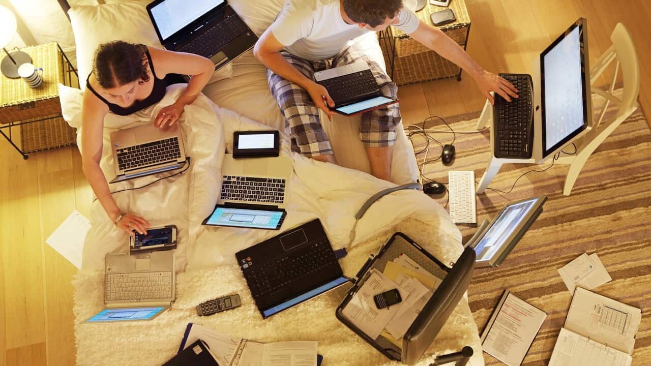 Couple in bed surrounded by computers