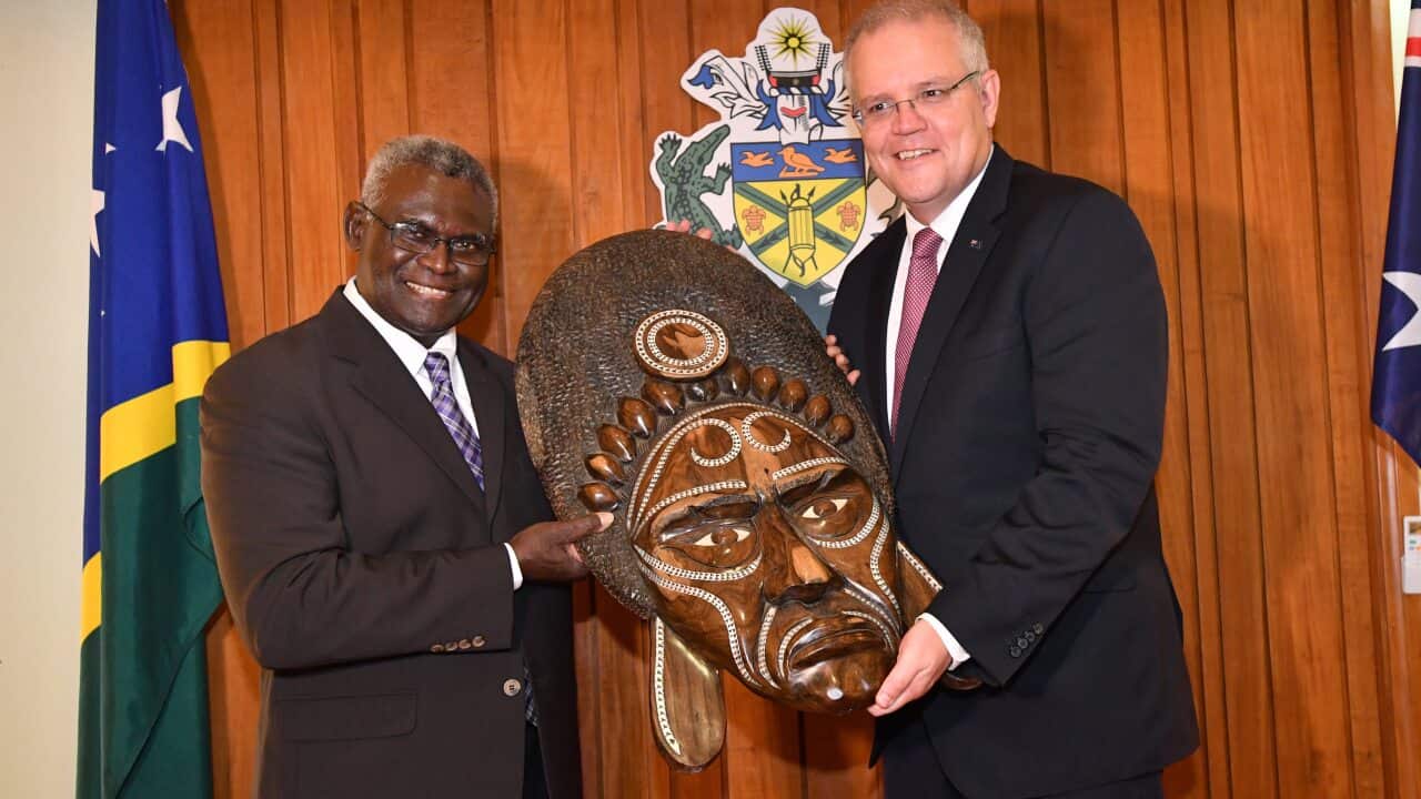 Solomon Islands Prime Minister Manasseh Sogavare (left) presents a traditional wood carving to the Australian Prime Minister Scott Morrison.