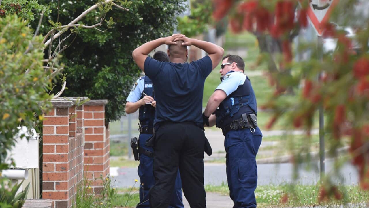 Police search a man during raids at Guildford