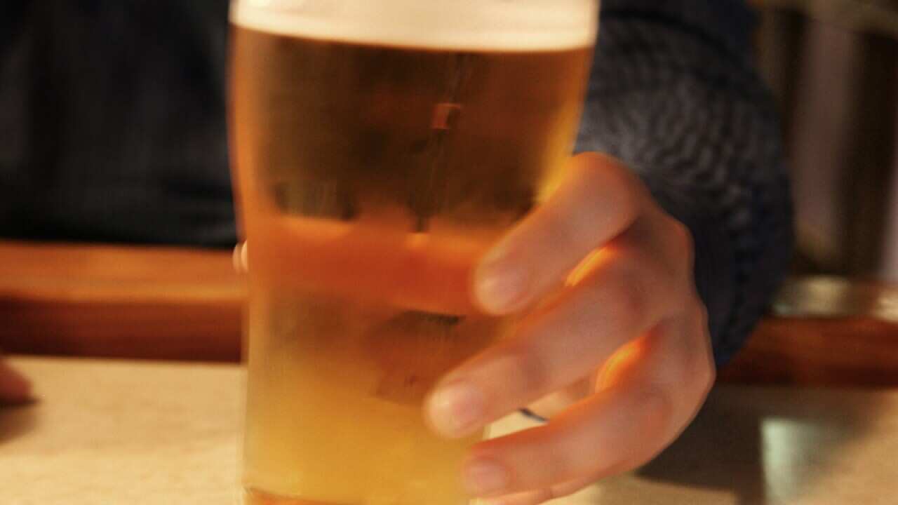 A person drinks a beer at a pub