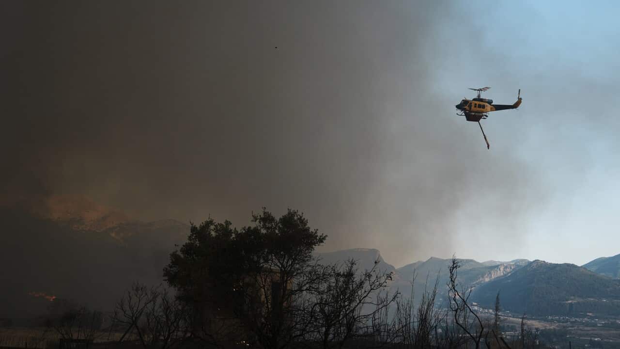 A helicopter can be seen flying over a burnt landscape