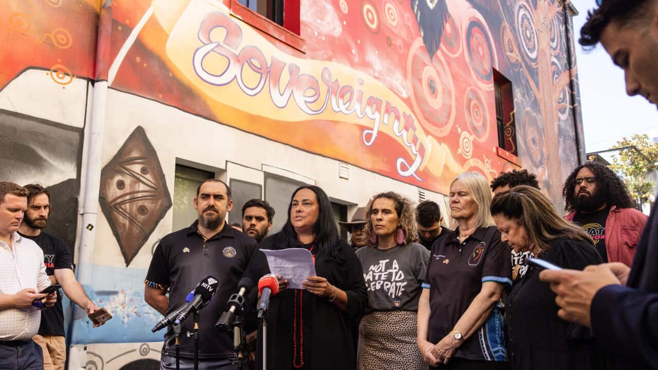 A group of people standing together. On the wall behind them is a mural that reads "Sovereignty".
