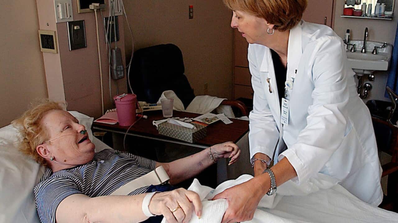 A woman receives help getting out of bed from palliative care specialist