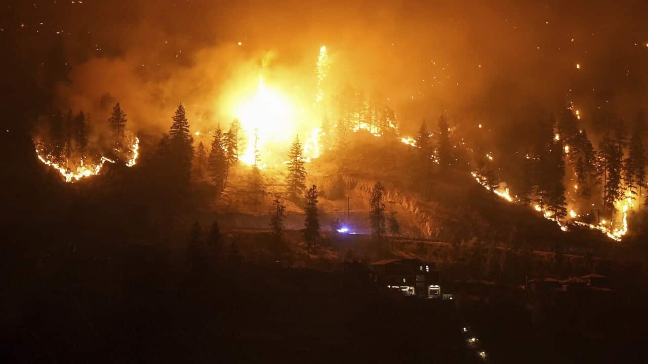 The McDougall Creek wildfire burns on the mountainside above a lakefront home in West Kelowna, lighting up the night time sky.