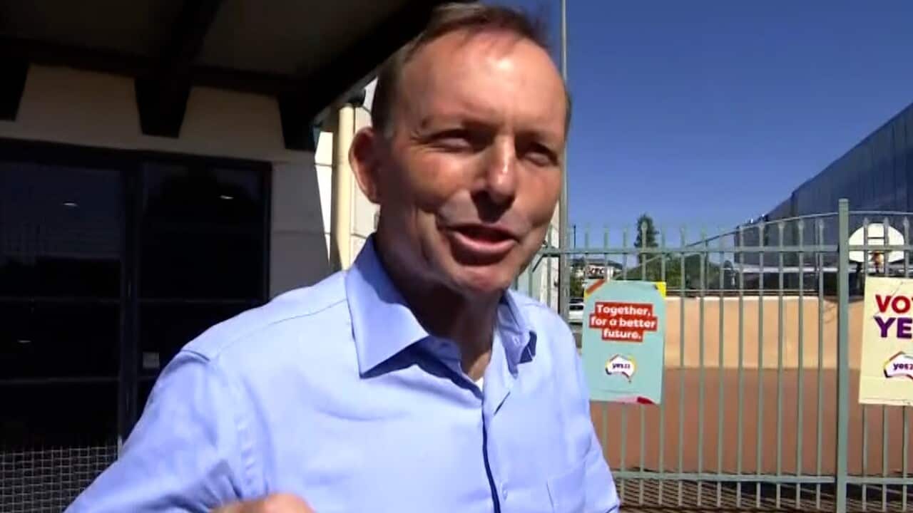 A man wearing a blue shirt walking outside.