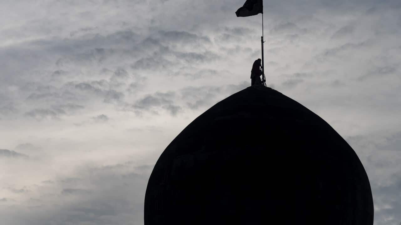 A Shia Muslim man erect flags on dome of an Imam Bara ahead