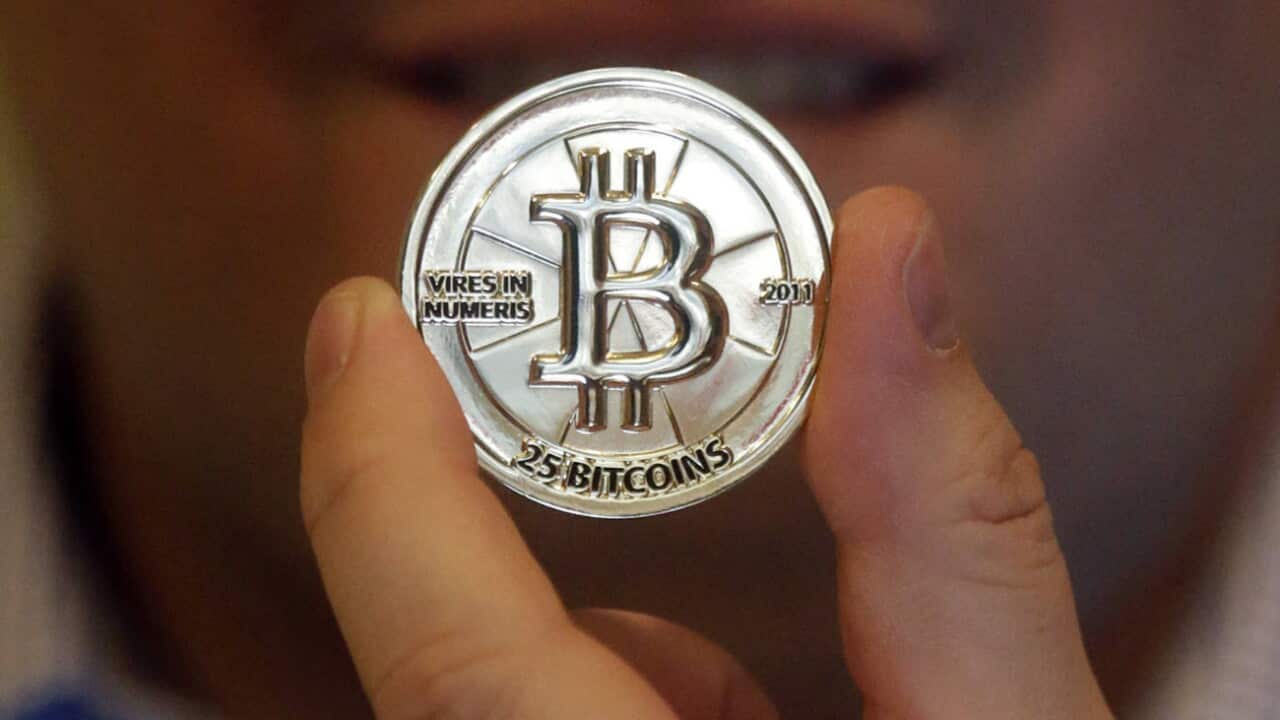  In this April 3, 2013 file photo, Mike Caldwell, a 35-year-old software engineer, holds a 25 Bitcoin token at his shop in Sandy, Utah.
