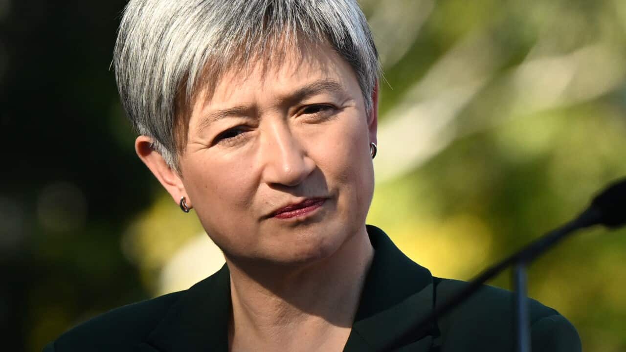 Woman in blazer looks past a microphone.