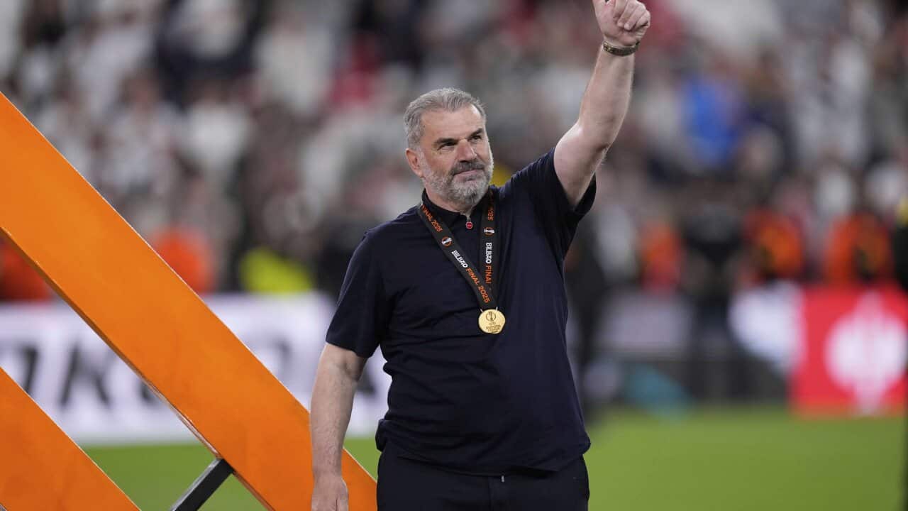 A man offers crowds a thumbs up at a football match.