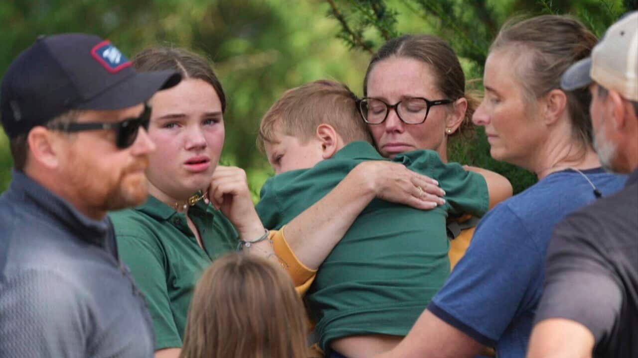 Parents comfort their children after a shooting at Annunciation Church on Wednesday