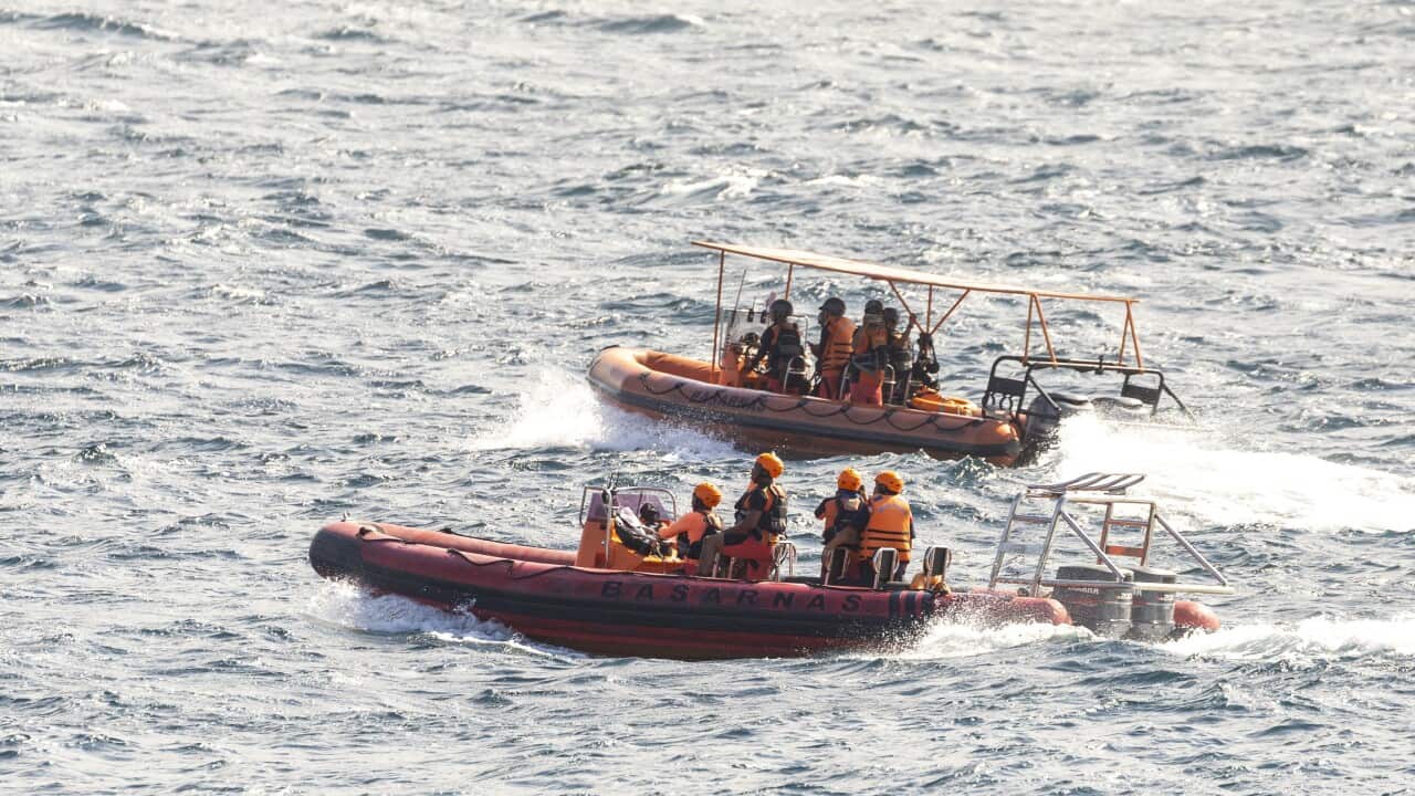 Two rescue boats with their crews aboard scan the waters, searching for survivors.